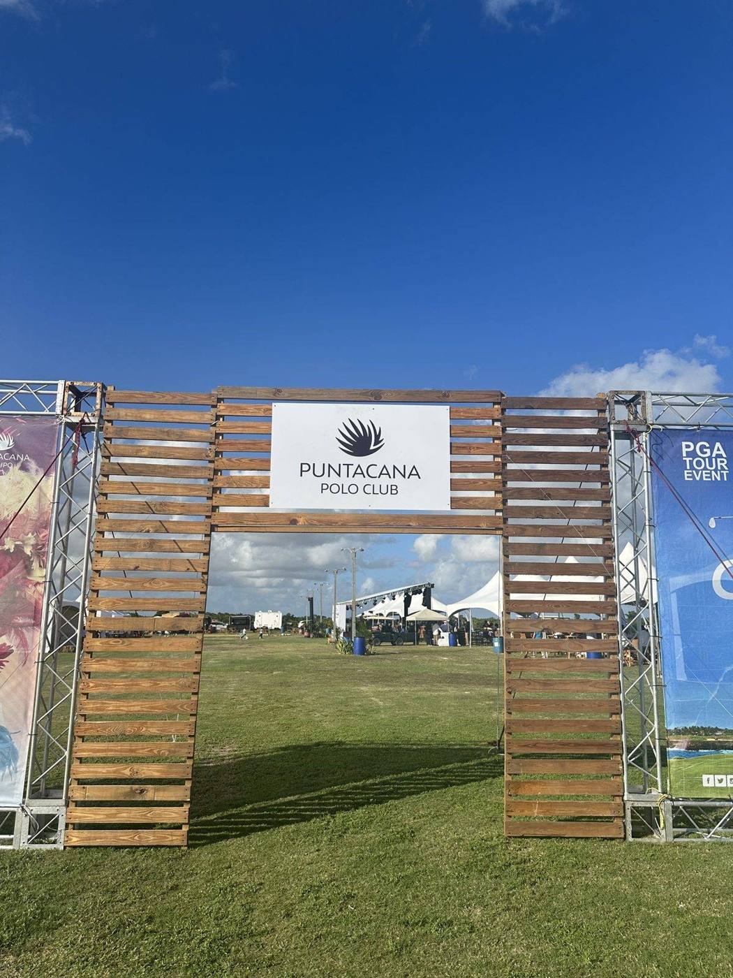 A wooden entrance arch for the Puntacana Polo Club event with tents on the field beyond