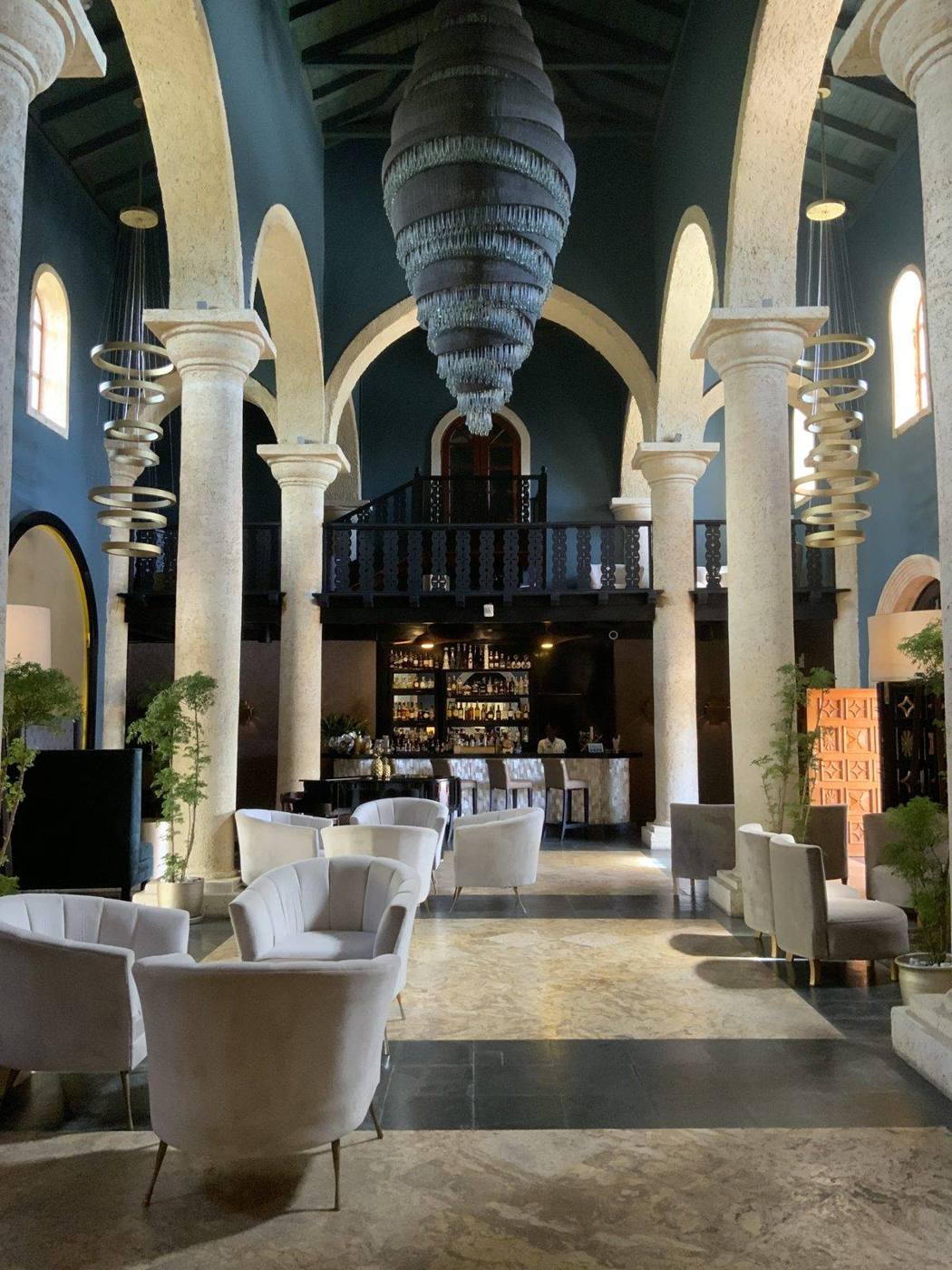 A grand resort lobby with arched columns, a dramatic hanging light sculpture and lounge seating
