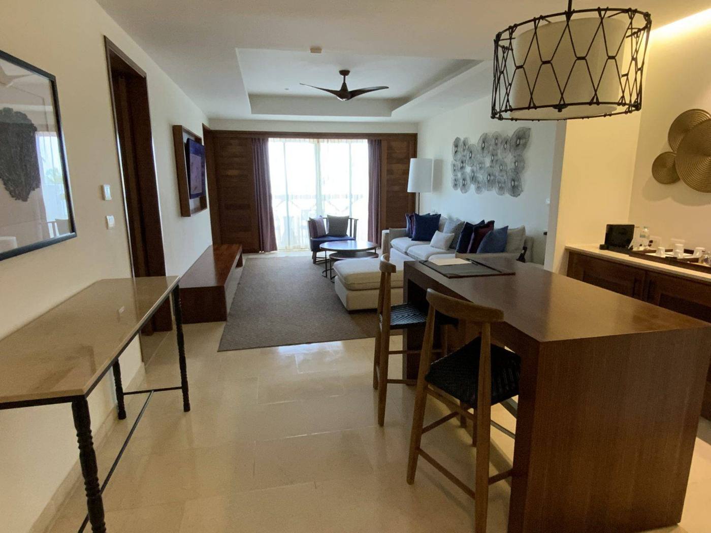 A resort suite with a dining table, a work desk and a sitting area with ocean light