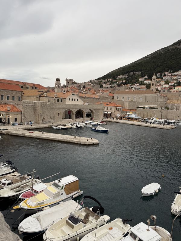 Small boats moored in Dubrovnik’s Old Port below the city walls and stone harbor buildings