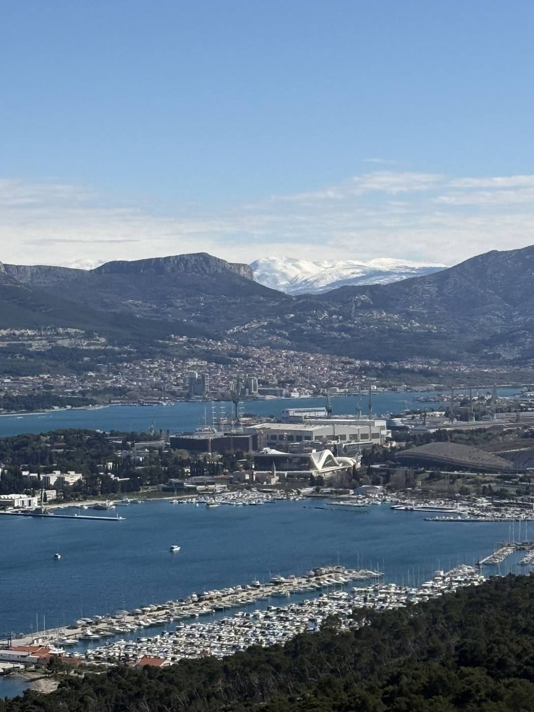 Split’s harbor, marinas and red-roofed neighborhoods seen from Marjan Hill, with snow-capped mountains behind
