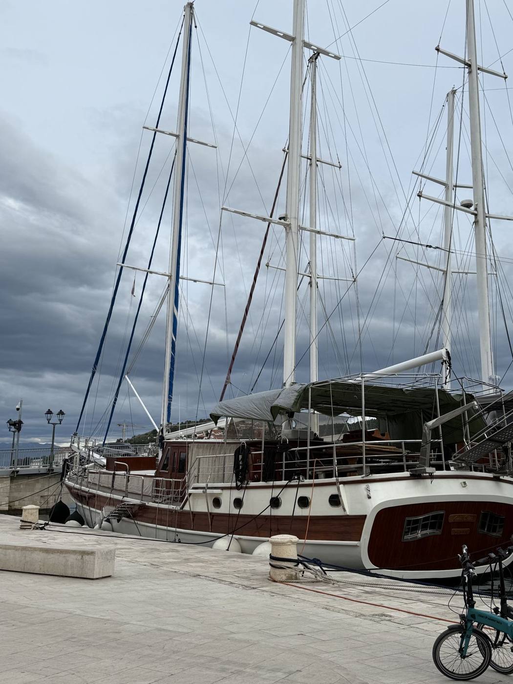 Wooden tall-masted sailing ships tied up along Trogir’s waterfront under gray clouds
