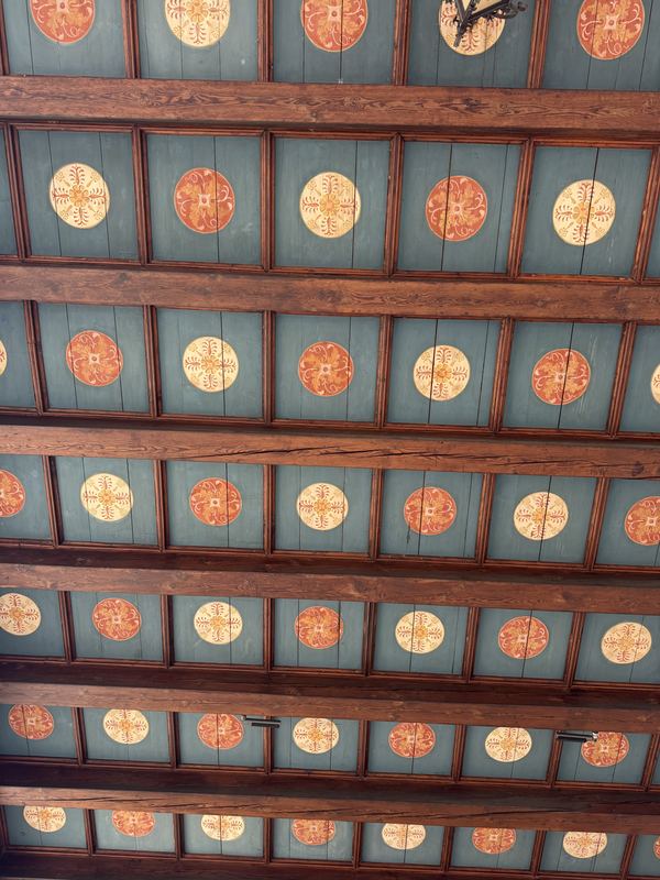 A painted wooden ceiling with rows of red and gold medallions in Trogir’s Town Loggia