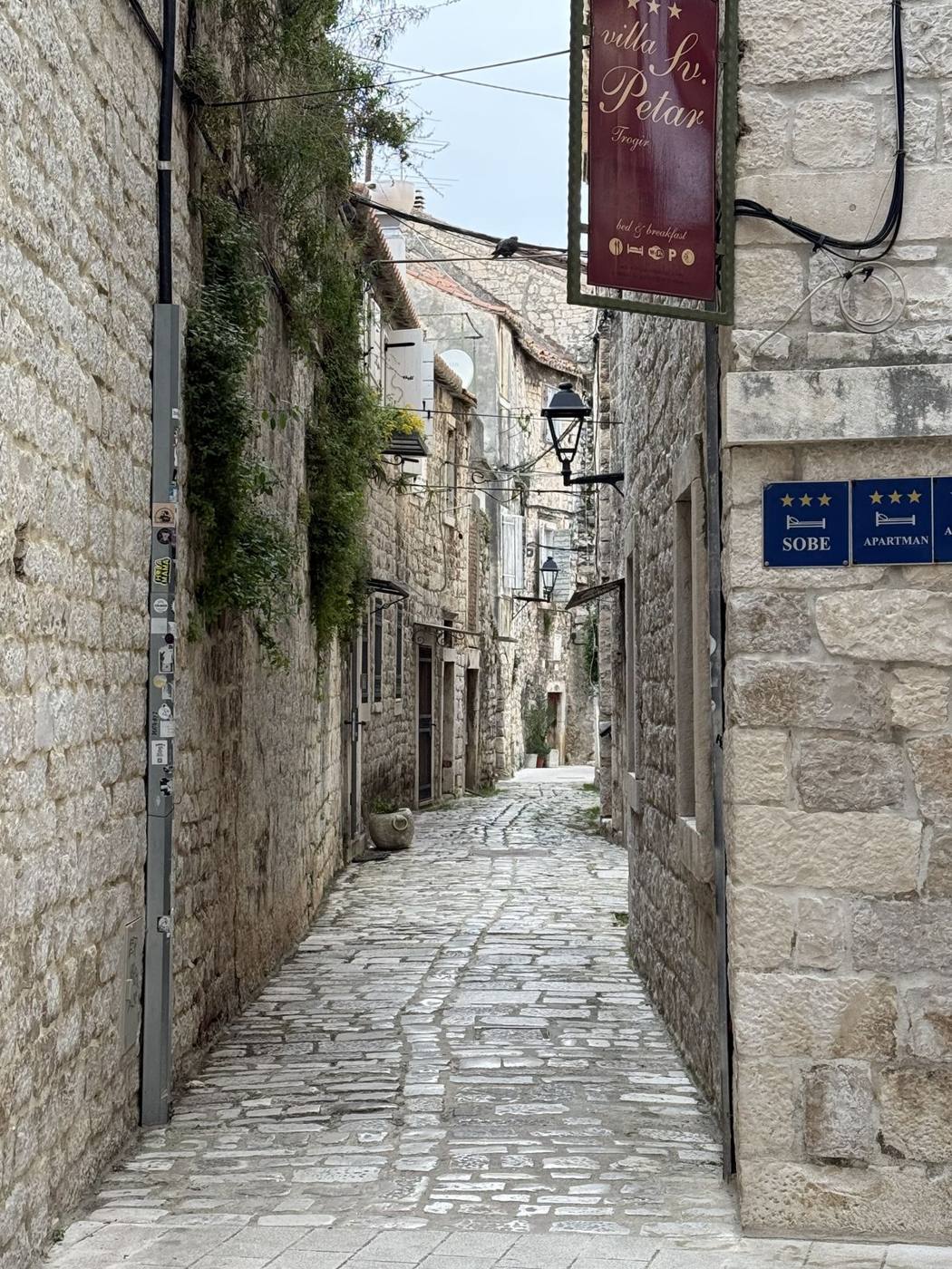 A narrow, cobbled medieval lane between stone houses in Trogir’s old town