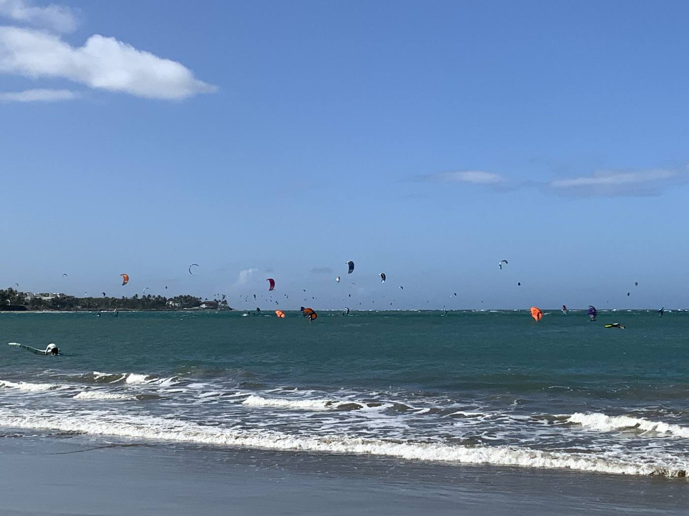 Dozens of colorful kites over the blue water of Cabarete Bay