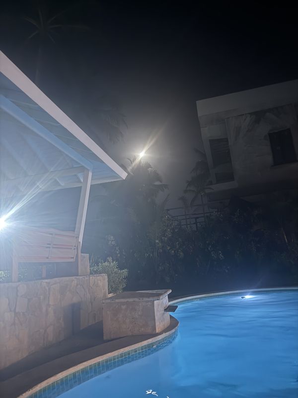 A villa pool glowing blue at night under the moon