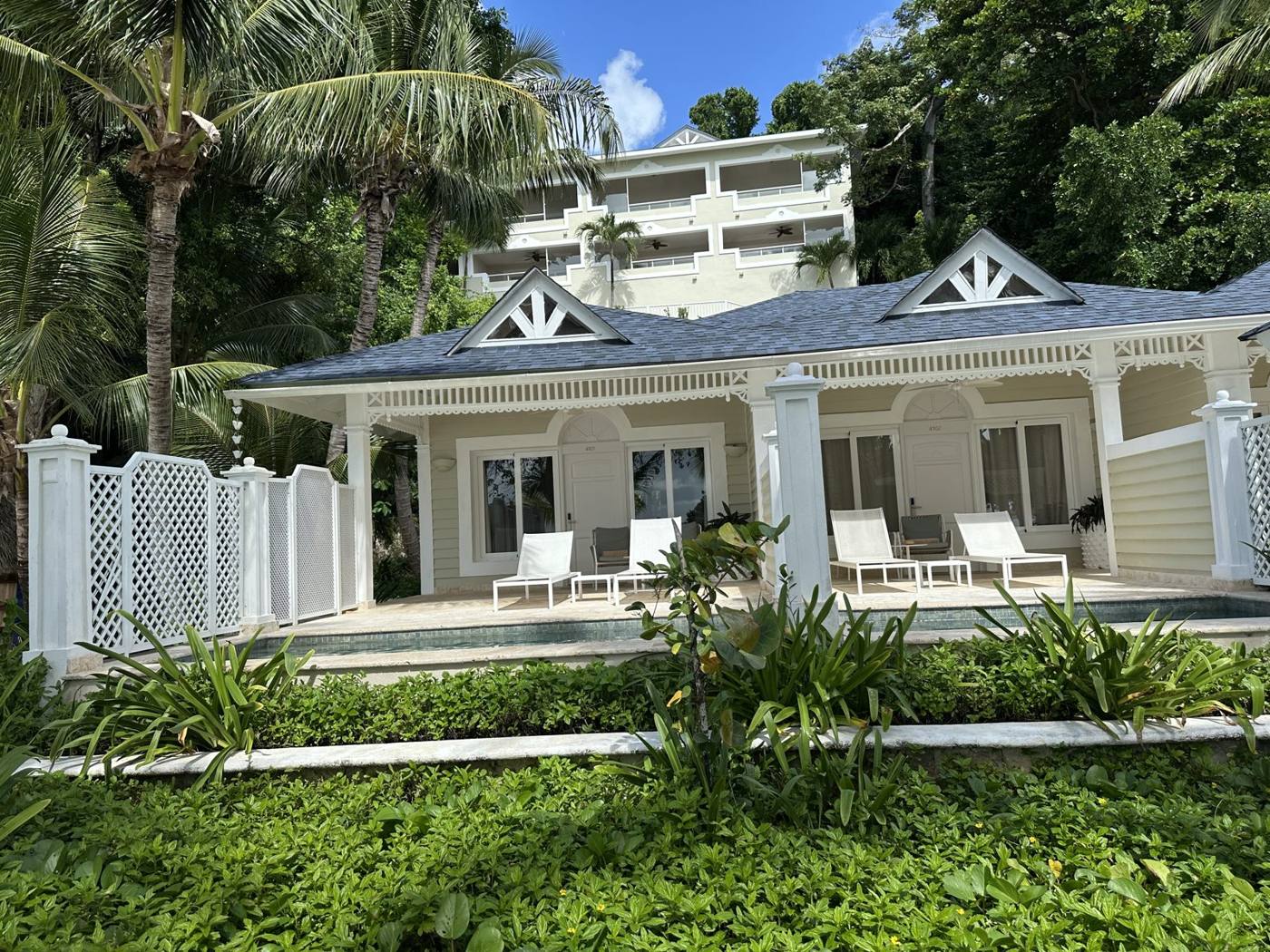 A white villa with a blue roof, lounge chairs and tropical gardens on the Samaná Peninsula