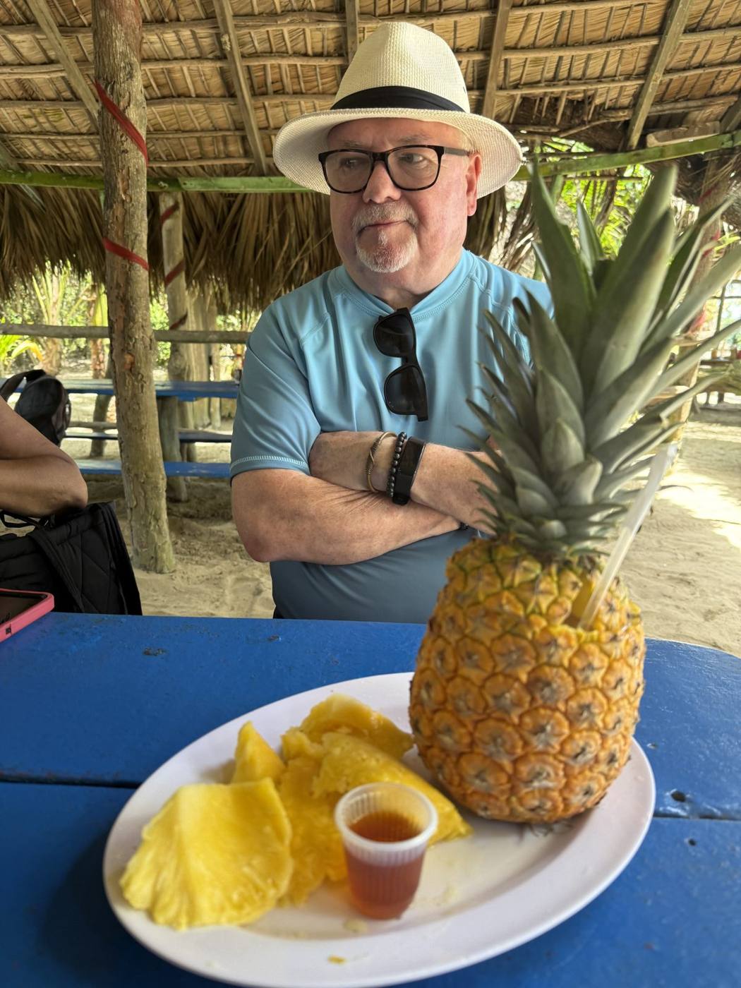 Troy Haley in a straw hat at a picnic table with a fresh pineapple and sliced fruit at La Boca