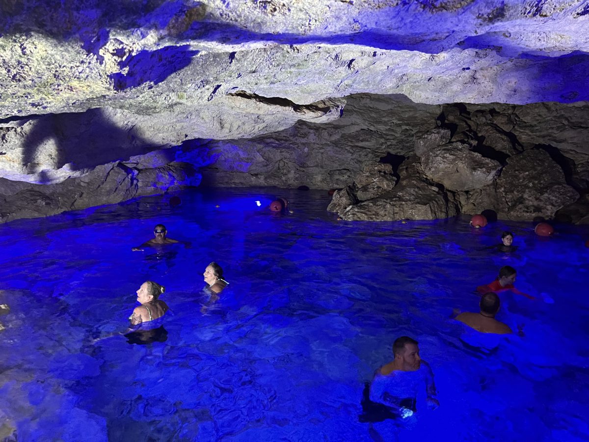 Swimmers in a blue-lit underground cave pool at Scape Park