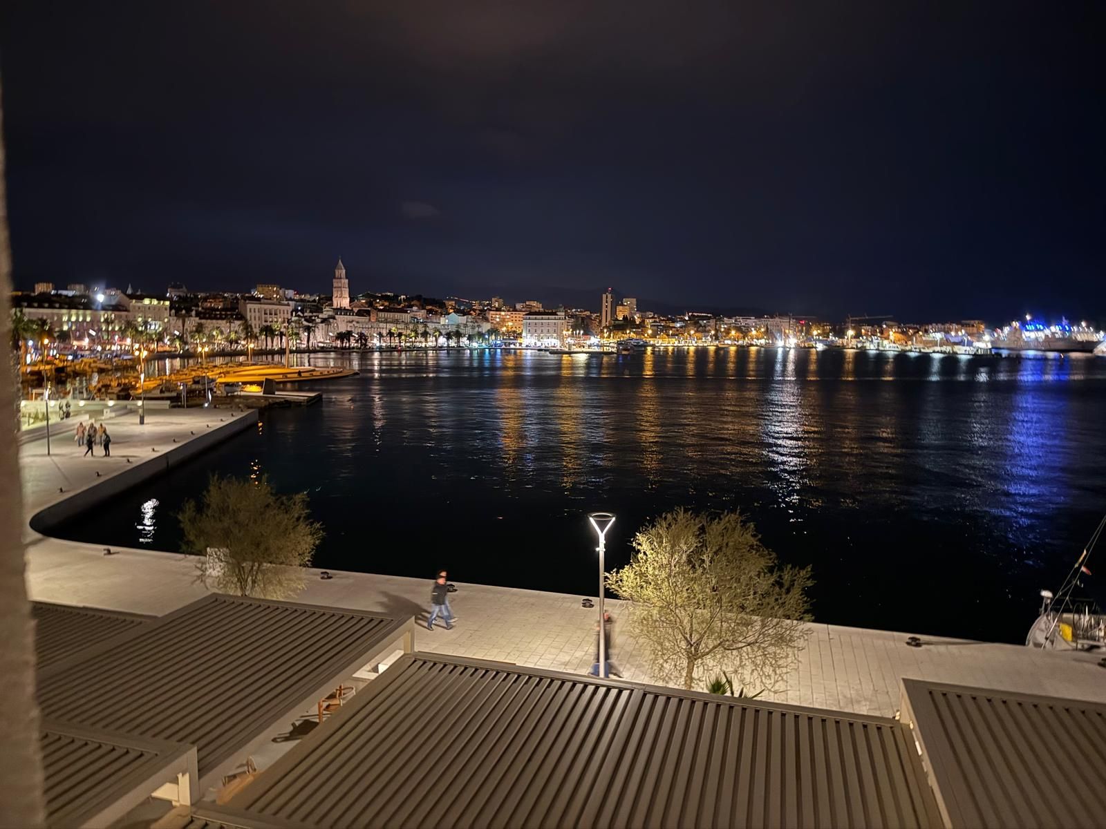 Split’s waterfront promenade at night, with the city lights and the cathedral bell tower reflected in the harbor